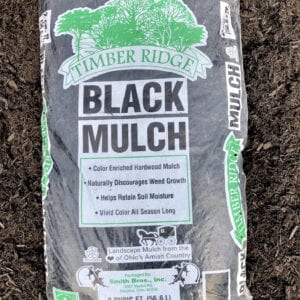 A bag of black mulch sitting on top of a pile.