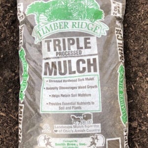 A bag of mulch that is on the ground.