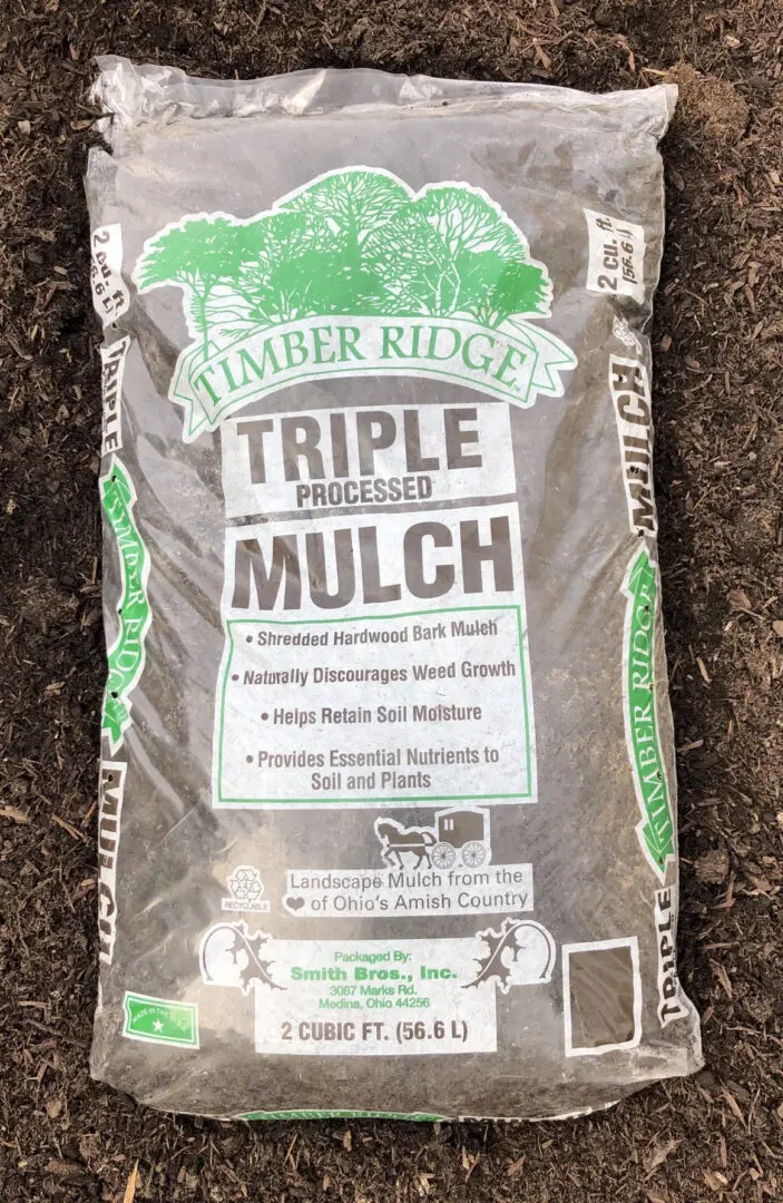 A bag of mulch that is on the ground.